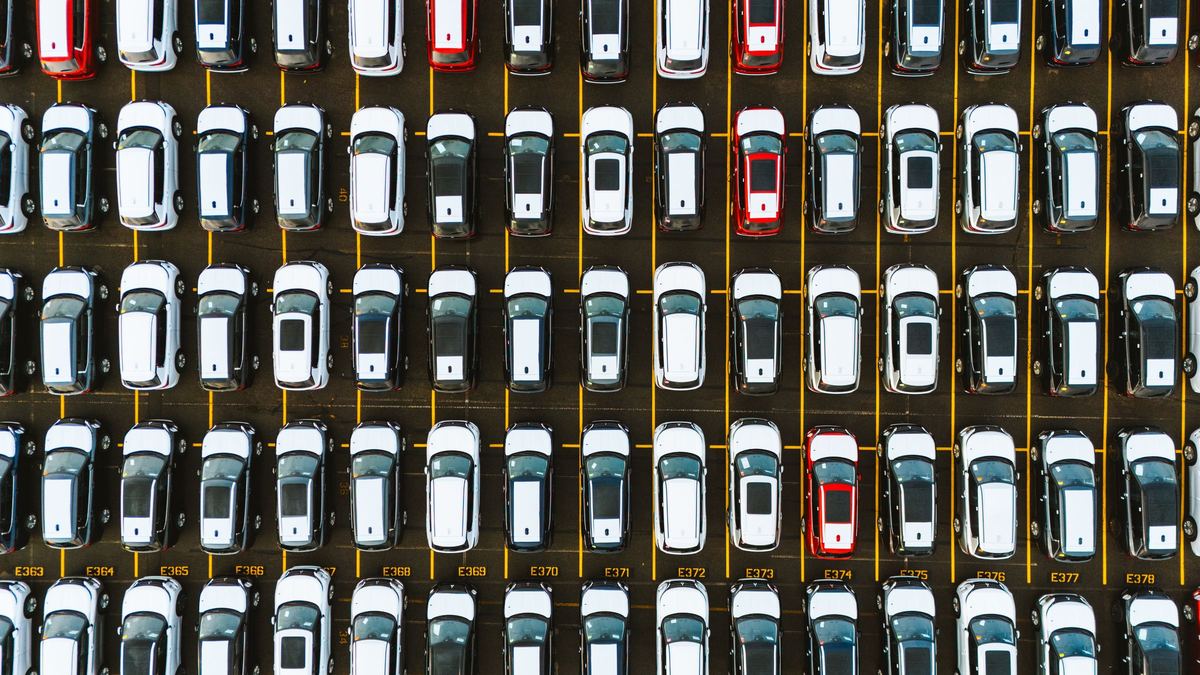 Rijen geparkeerde wagens van bovenaf gezien, met één rode wagen tussen de witte