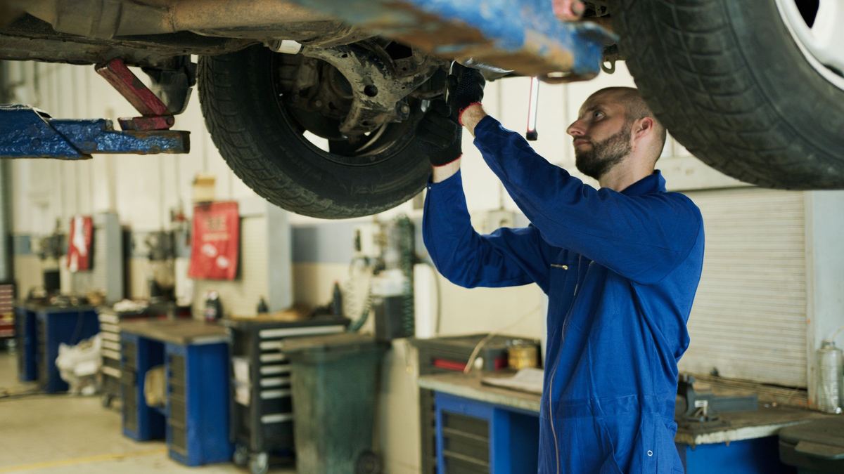 Een mechanieker werkt aan de onderkant van een wagen op de brug